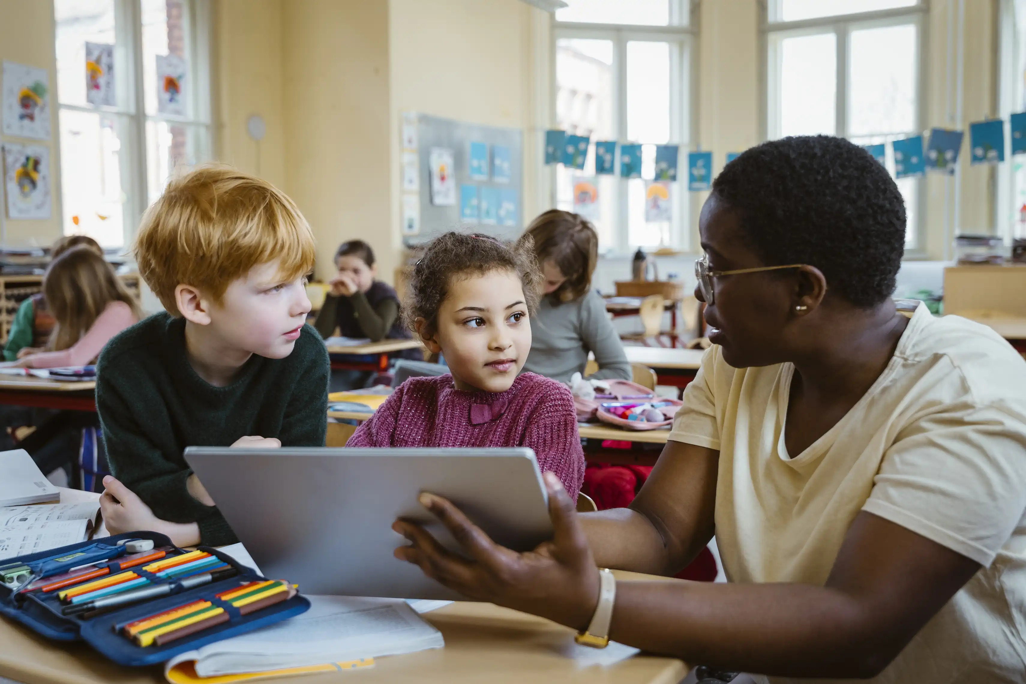 teacher showing something to students on tablet