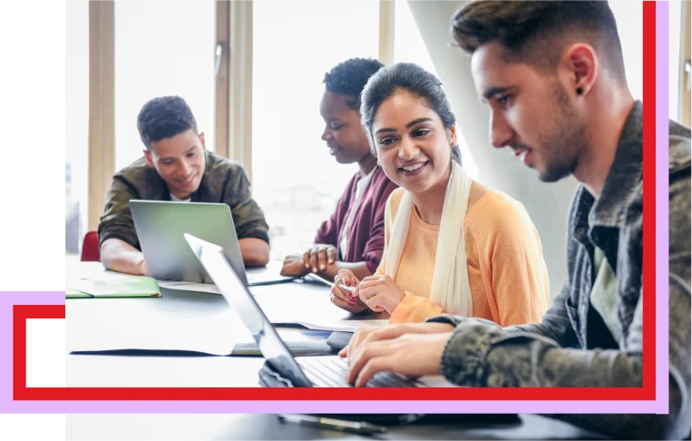 Image of students sitting on a desk using their laptops
