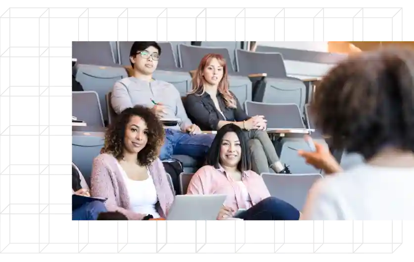 Group of diverse students in a classroom listening to an instructor.