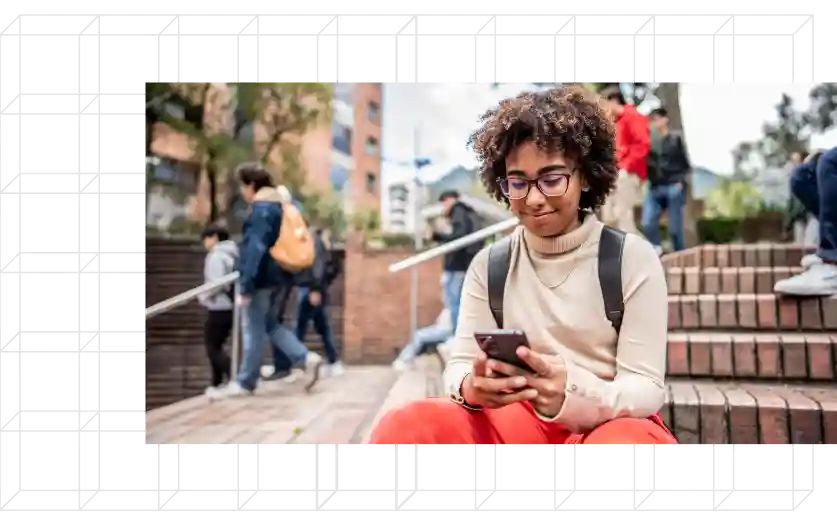 Young student sitting on steps looking at phone.