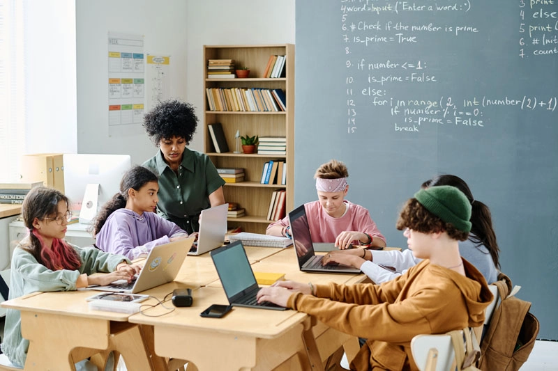 students sitting at table using laptops