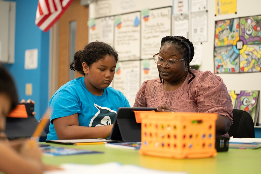 teacher helping student on a tablet